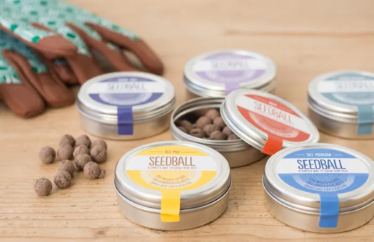 tins of seeds with coloured labels seedball